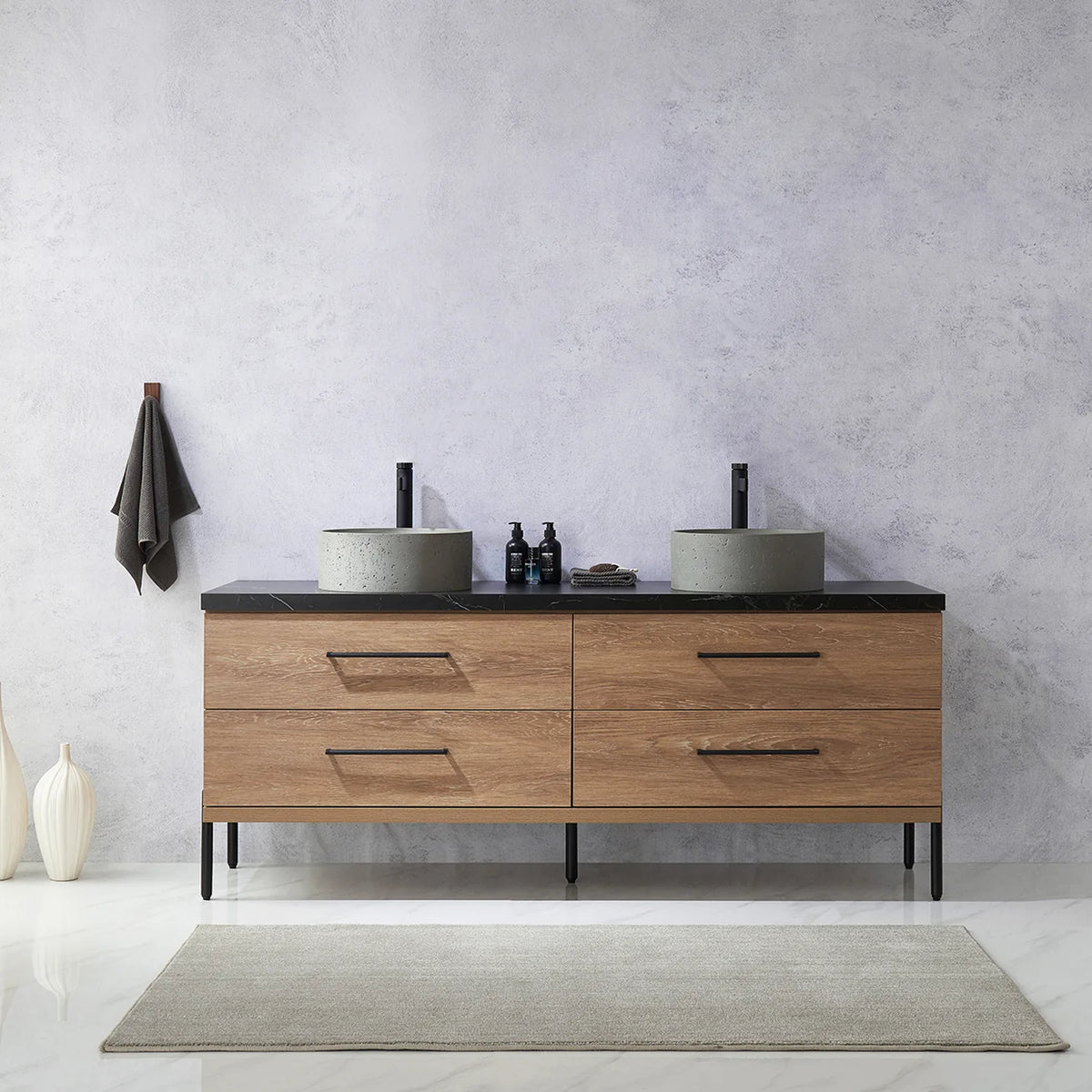 Pale plaster wall, white vases and a hanging towel behind the oak vanity on black legs