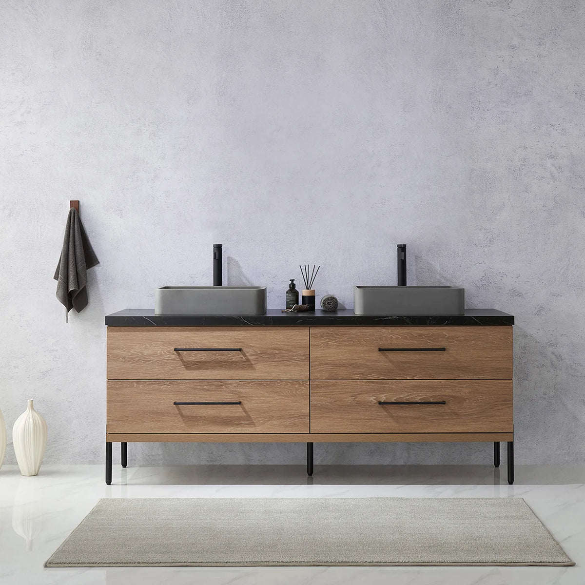 Pale plaster wall, white vases and a hanging towel behind the oak vanity on black legs