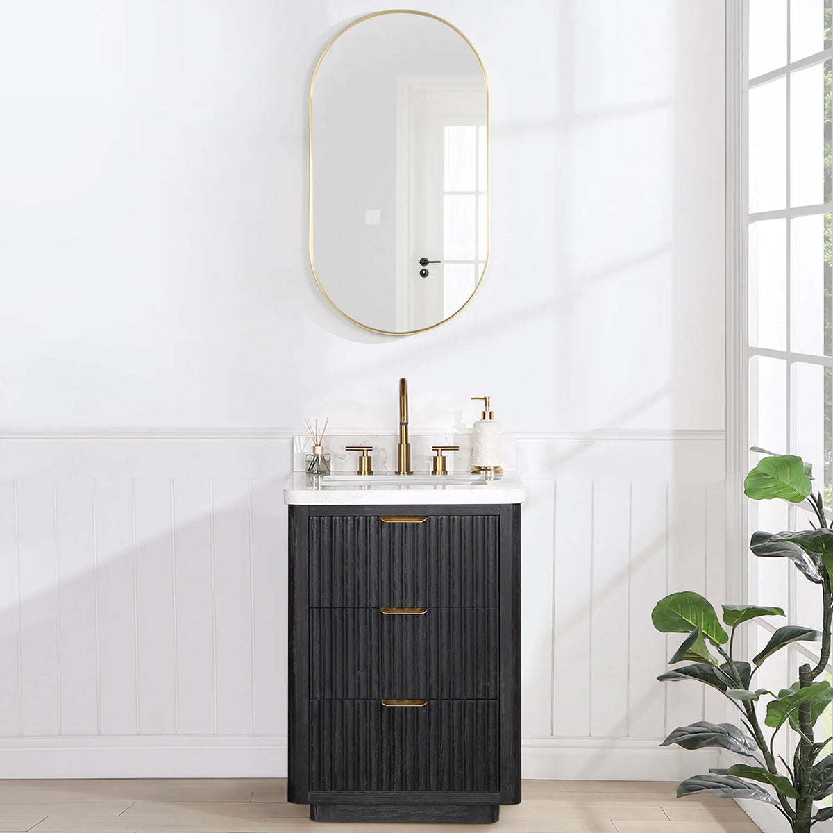 Room scene: 24 inch single vanity under an oval wall mirror, plant at the right, window light at the side