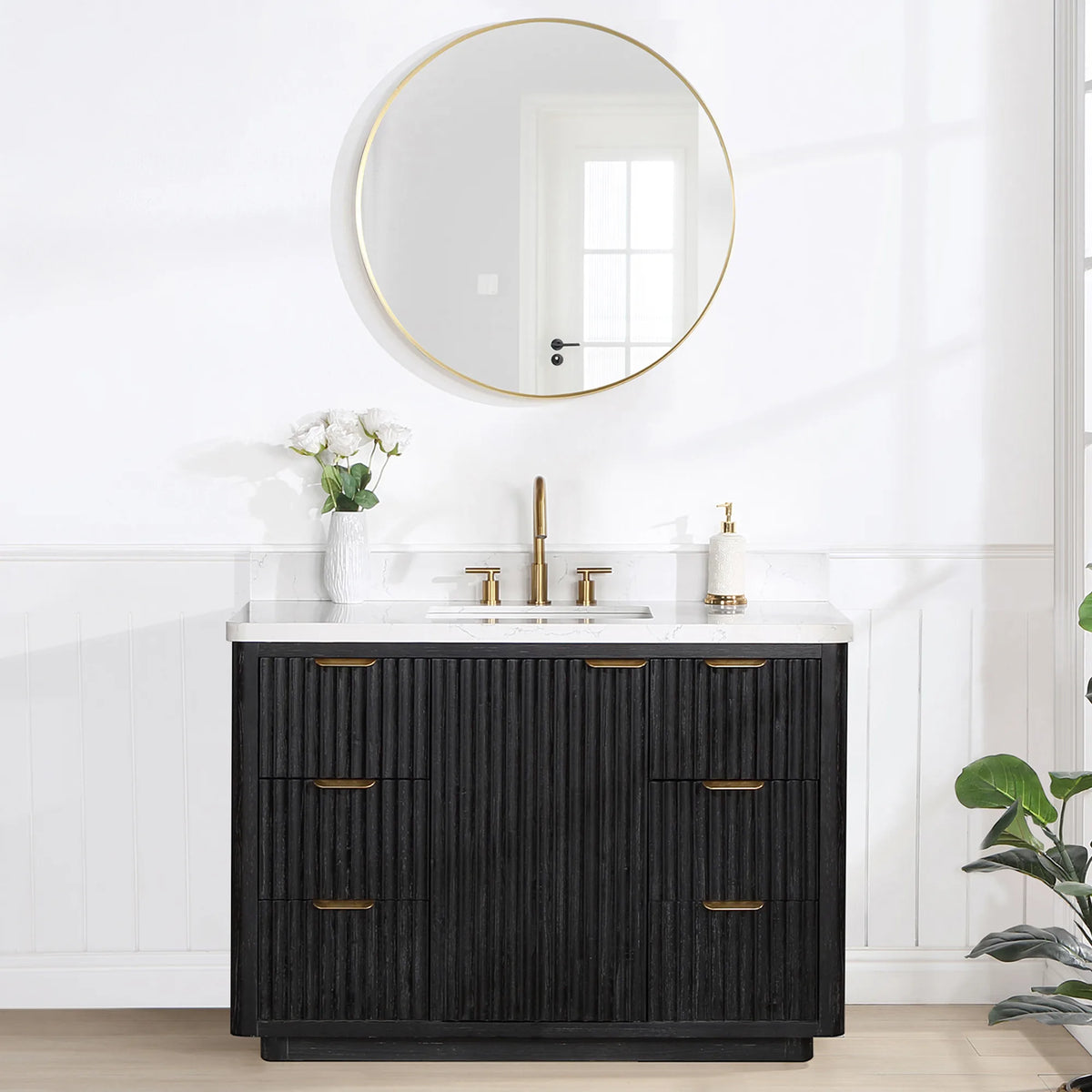Room scene: 48 inch vanity below a circular wall mirror, white flowers on the top and a plant at the right